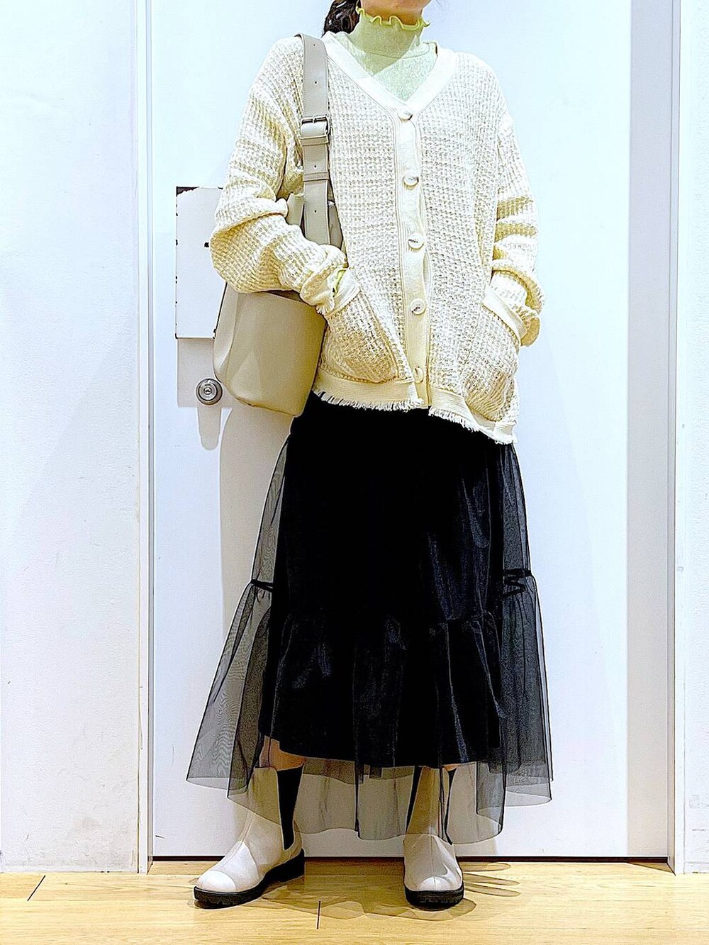 グレー系のショルダーバッグ、ベージュ系のブーツ、ブラック系のスカートを着用したレディースの冬コーディネートの6枚目の写真