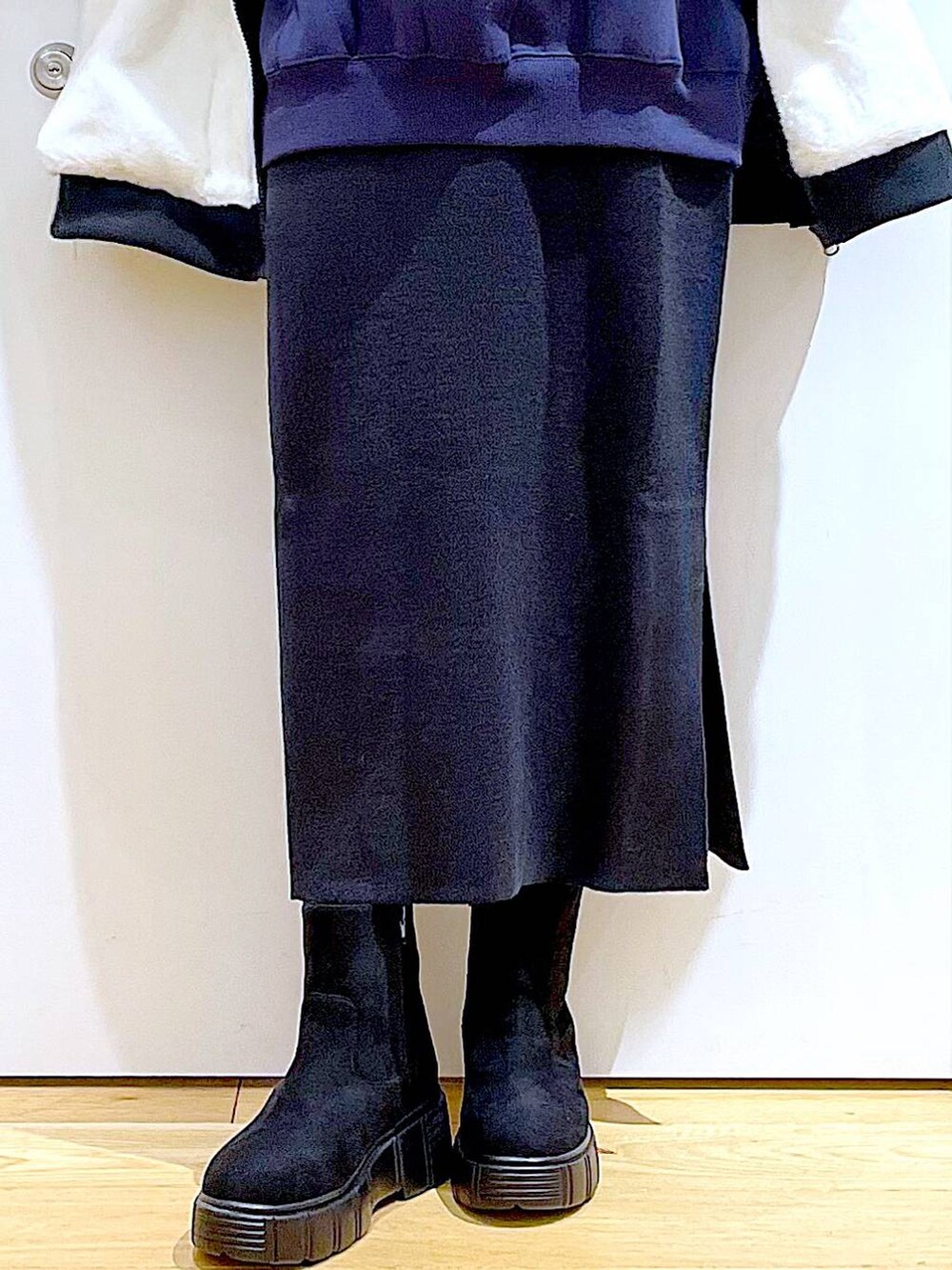 グレー系のスカート、ホワイト系のブルゾン、ブラック系のブーツを着用したレディースの冬コーディネートの8枚目の写真