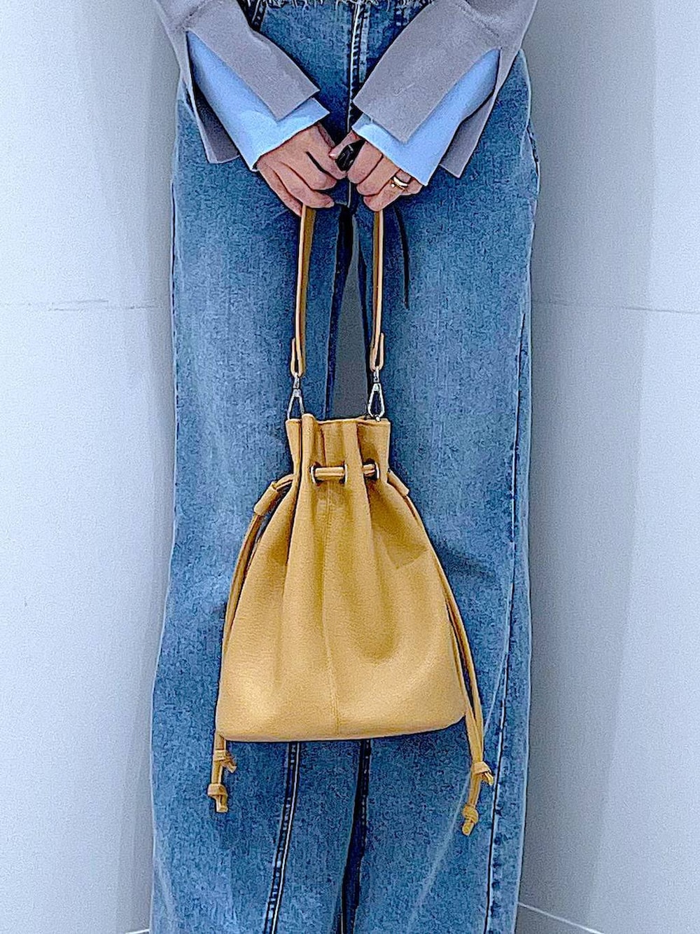 ホワイト系のベスト、グレー系のニット/セーター、ブルー系のデニムパンツを着用したレディースの春コーディネートの9枚目の写真