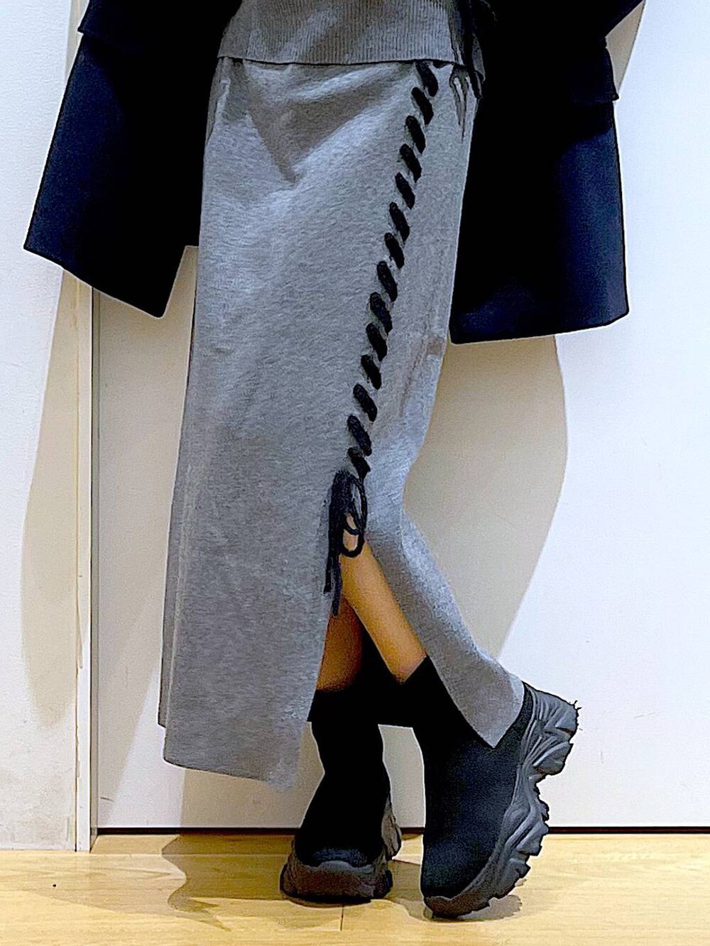 ブルー系のステンカラーコート、ホワイト系のハンドバッグ、ブラック系のブーツを着用したレディースの冬コーディネートの8枚目の写真