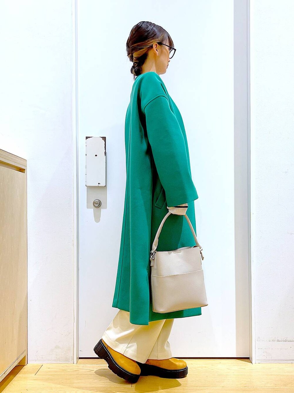 グレー系のショルダーバッグ、ホワイト系のニット/セーター、ベージュ系のブーツを着用したレディースの冬コーディネートの4枚目の写真