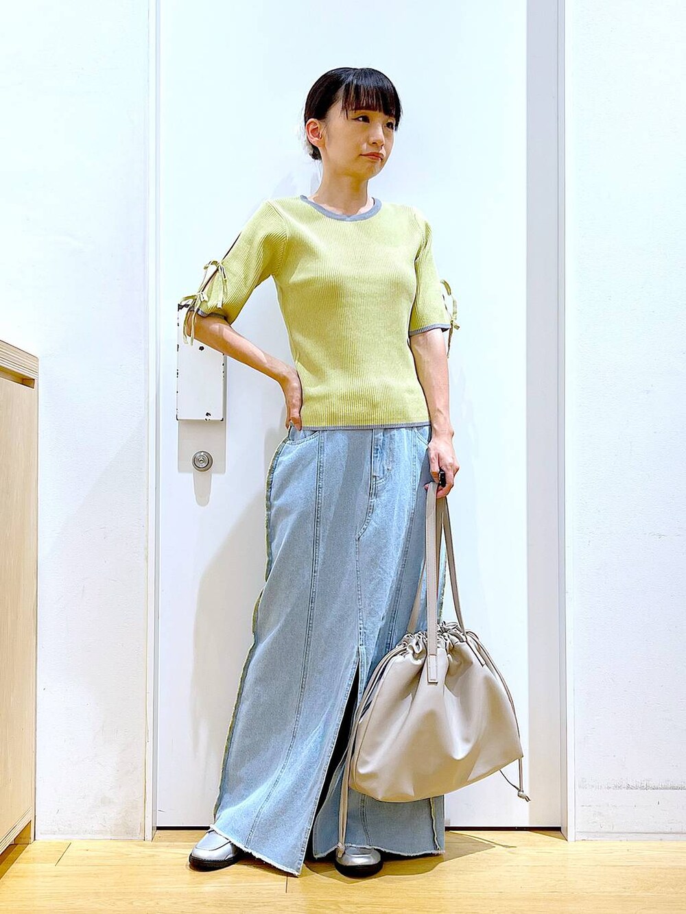 ベージュ系のトートバッグ、シルバー系のローファー、イエロー系のニット/セーターを着用したレディースの秋コーディネートの2枚目の写真