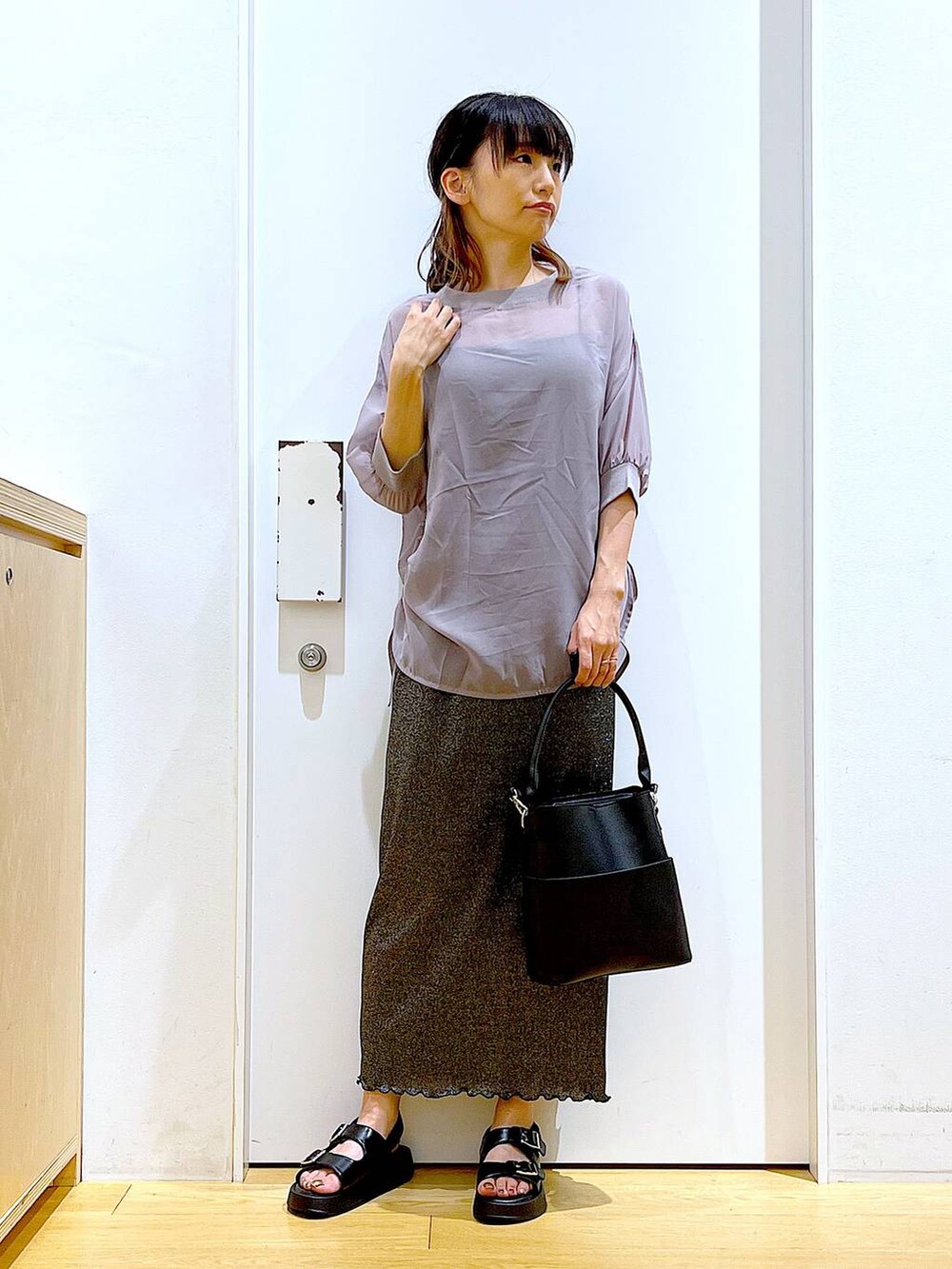 ブラック系のスカート、ブラック系のショルダーバッグ、ブラック系のサンダルを着用したレディースの夏コーディネートの2枚目の写真