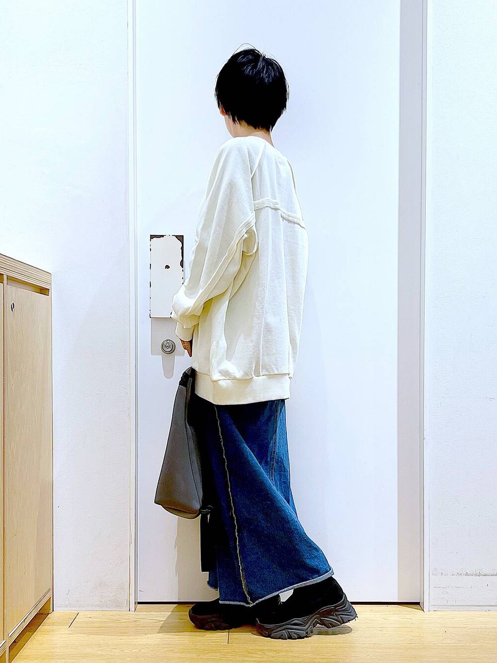 ブルー系のデニムスカート、グレー系のバックパック/リュック、ブラック系のブーツを着用したレディースの冬コーディネートの3枚目の写真