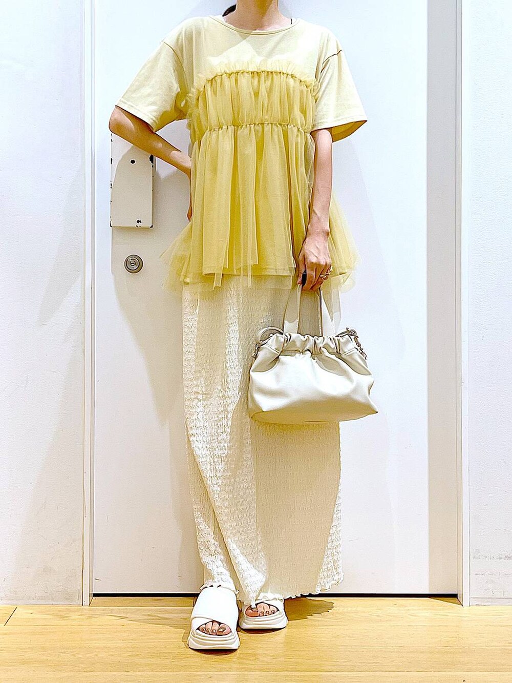 ホワイト系のサンダル、ベージュ系のスカート、イエロー系のTシャツ/カットソーを着用したレディースの夏コーディネートの6枚目の写真