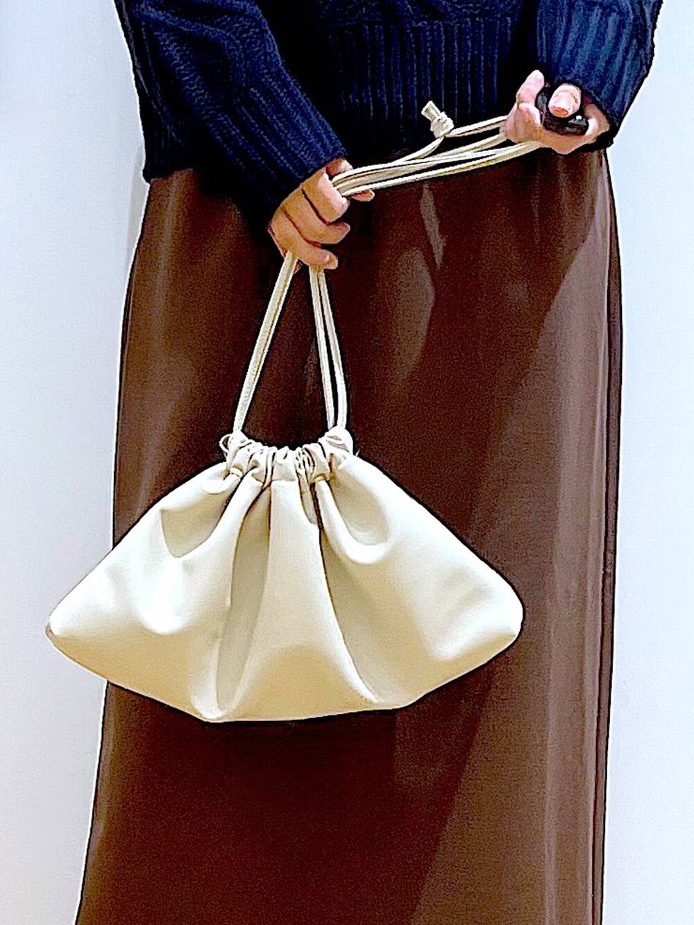 ブラック系のブーツ、ベージュ系のショルダーバッグ、ブラウン系のスカートを着用したレディースの冬コーディネートの9枚目の写真