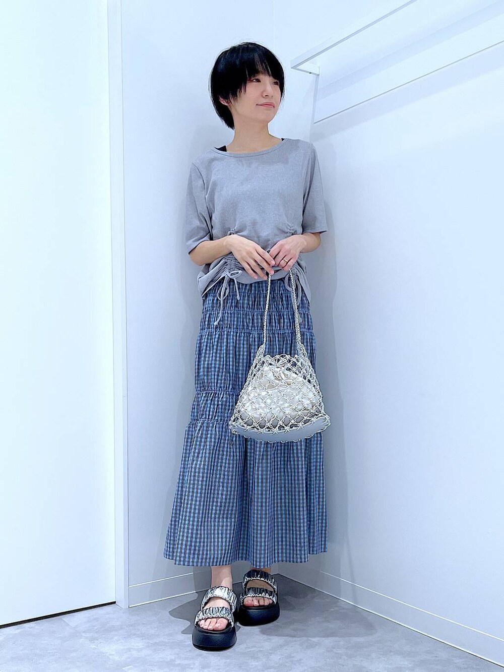 シルバー系のかごバッグ、シルバー系のサンダル、ブルー系のスカートを着用したレディースの夏コーディネートの2枚目の写真