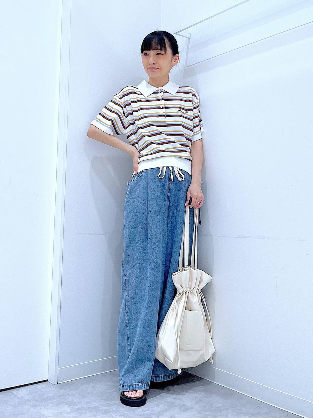 ブラック系のサンダル、ブルー系のデニムパンツ、ホワイト系のトートバッグを着用したレディースの夏コーディネートの2枚目の写真