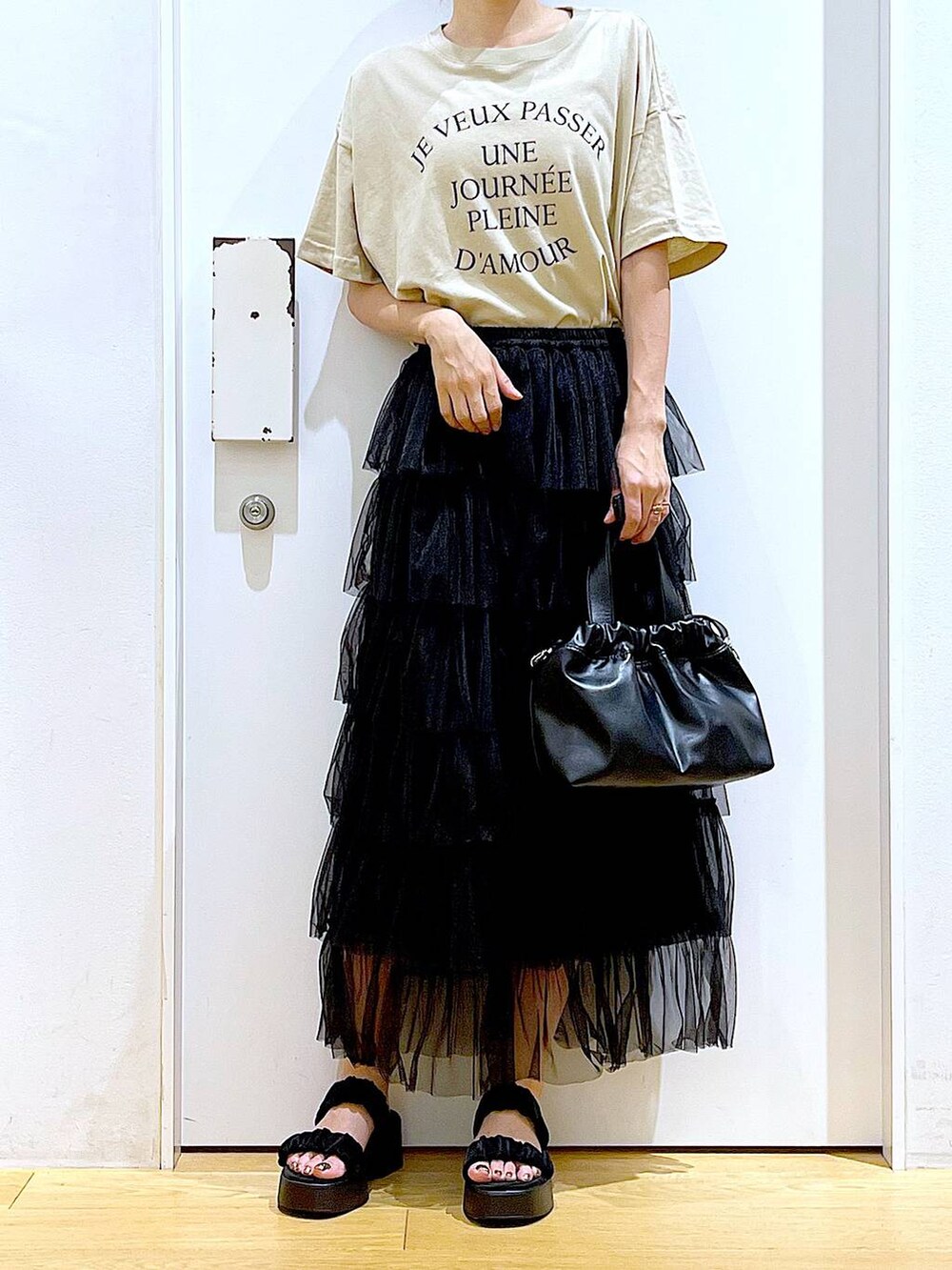 ブラック系のサンダル、ブラック系のショルダーバッグ、ブラック系のスカートを着用したレディースの夏コーディネートの6枚目の写真