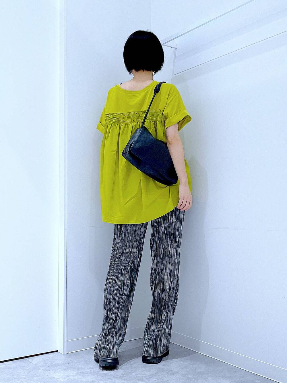 ブラック系のスニーカー、ブラック系のショルダーバッグ、グリーン系のTシャツ/カットソーを着用したレディースの夏コーディネートの5枚目の写真