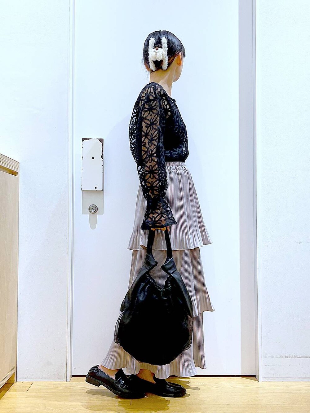 グレー系のスカート、ブラック系のトートバッグ、ブラック系のローファーを着用したレディースの秋コーディネートの4枚目の写真