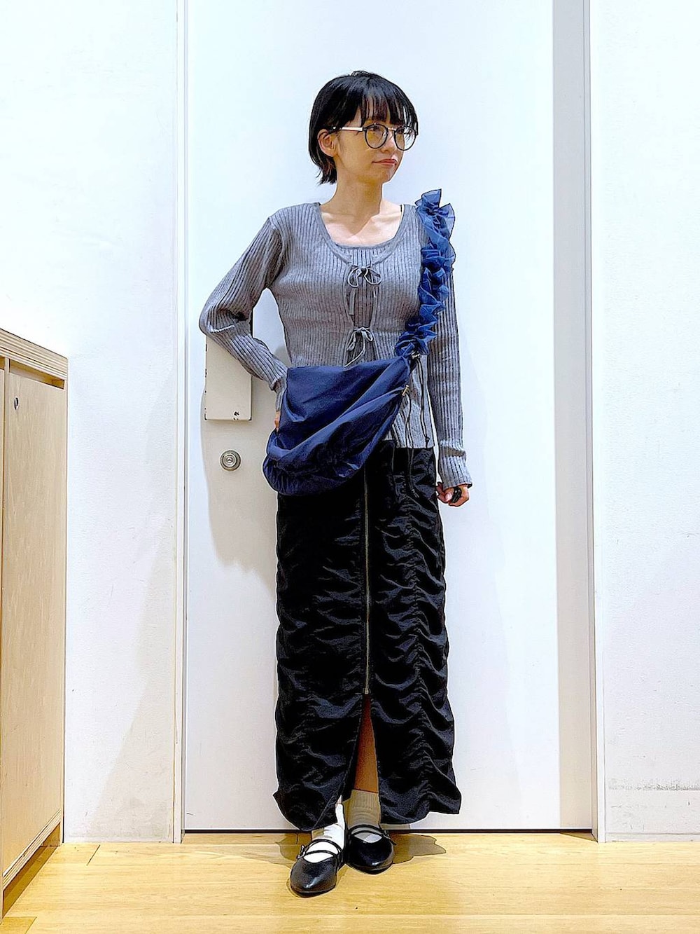 ブラック系のパンプス、ブルー系のショルダーバッグ、グレー系のカーディガン/ボレロを着用したレディースの秋コーディネートの2枚目の写真