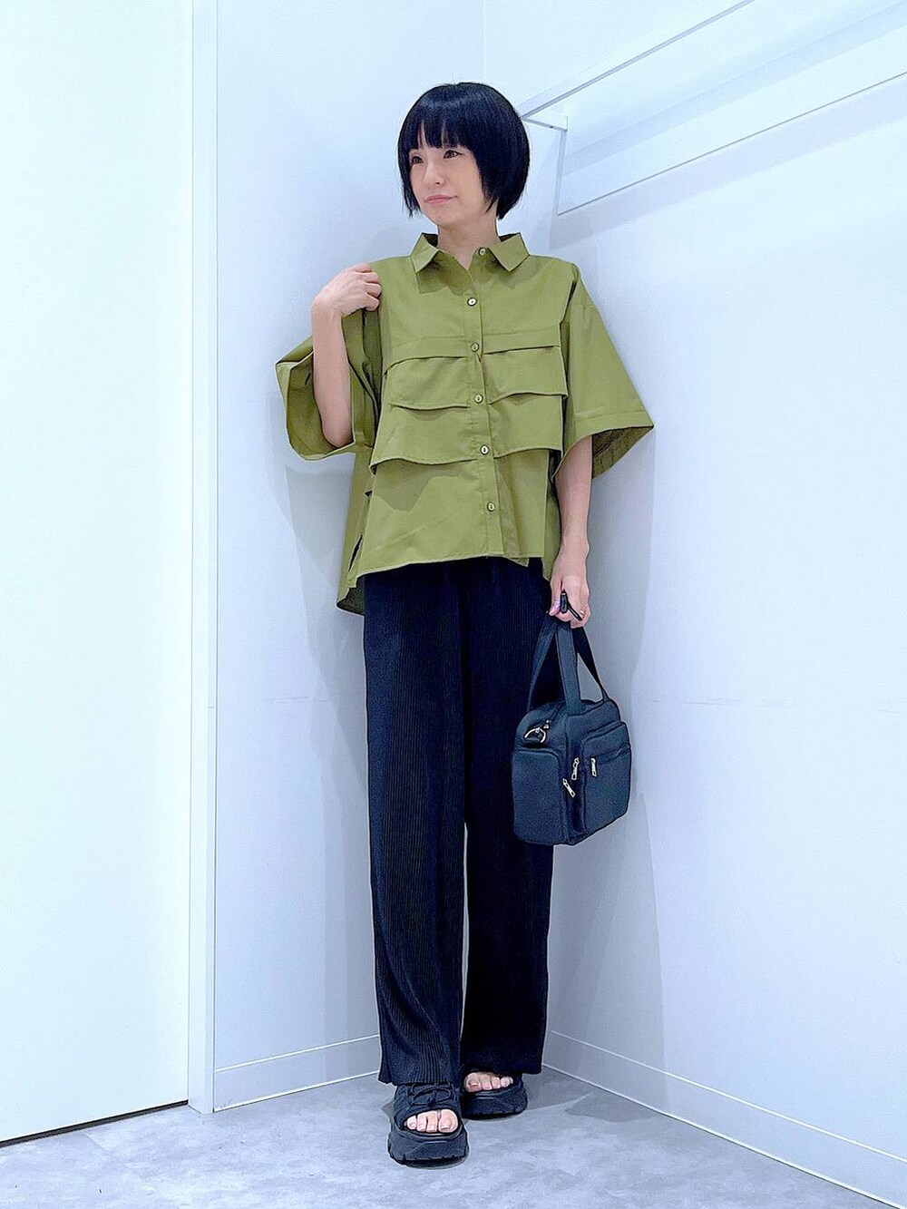 ブラック系のスニーカー、ブラック系のショルダーバッグ、グリーン系のシャツ/ブラウスを着用したレディースの夏コーディネートの2枚目の写真