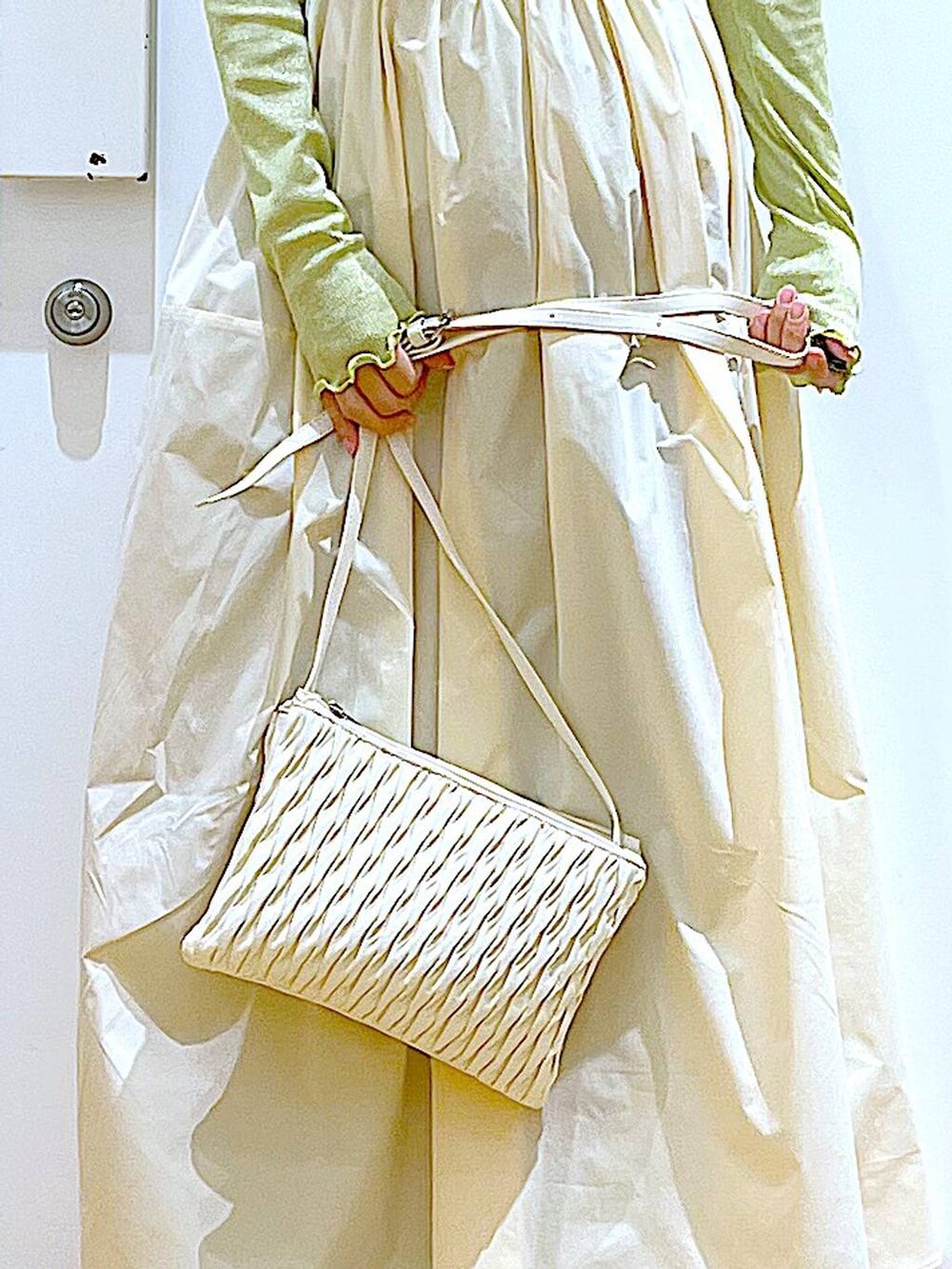 ホワイト系のショルダーバッグ、ベージュ系のブーツ、ブルー系のデニムパンツを着用したレディースの冬コーディネートの9枚目の写真