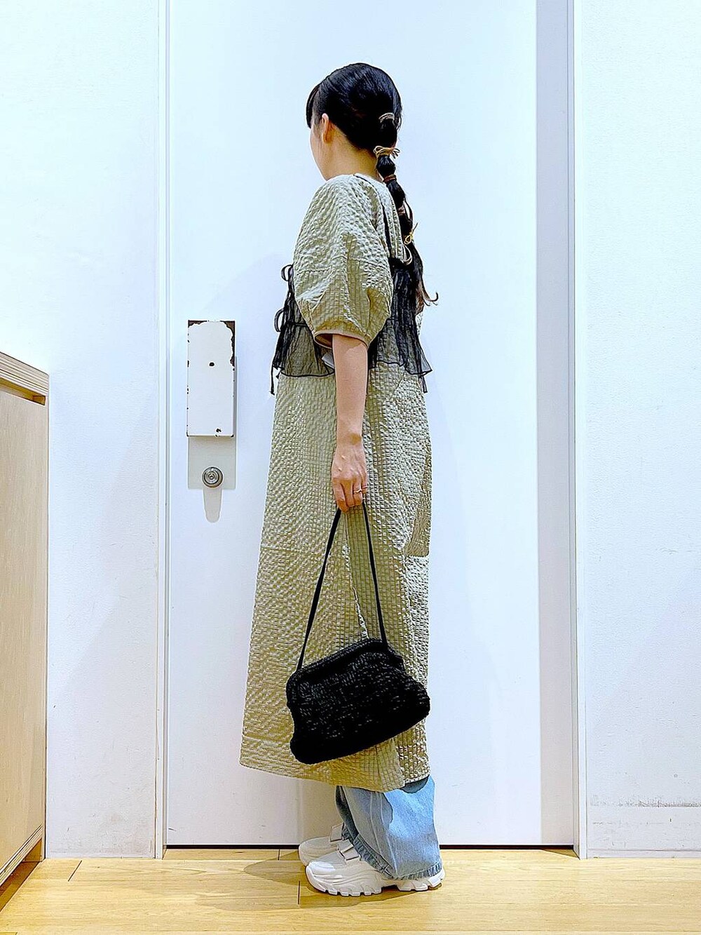 ホワイト系のスニーカー、ブルー系のデニムパンツ、ブラック系のショルダーバッグを着用したレディースの春コーディネートの3枚目の写真