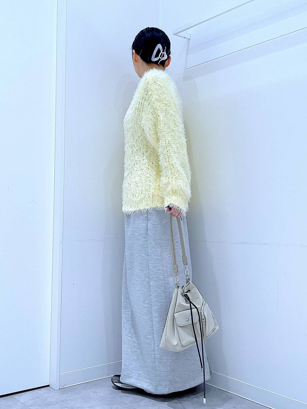 イエロー系のニット/セーター、グレー系のスカート、パープル系のバレッタ/ヘアクリップを着用したレディースの冬コーディネートの3枚目の写真
