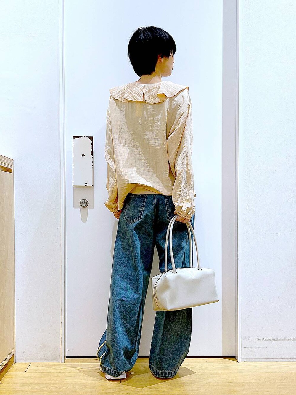ホワイト系のボストンバッグ、ホワイト系のスニーカー、ブルー系のデニムパンツを着用したレディースの春コーディネートの5枚目の写真