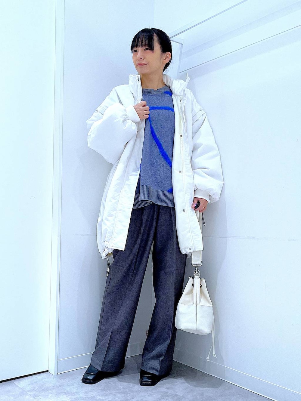 ホワイト系のブルゾン、ホワイト系のショルダーバッグ、ブラック系のブーツを着用したレディースの冬コーディネートの2枚目の写真