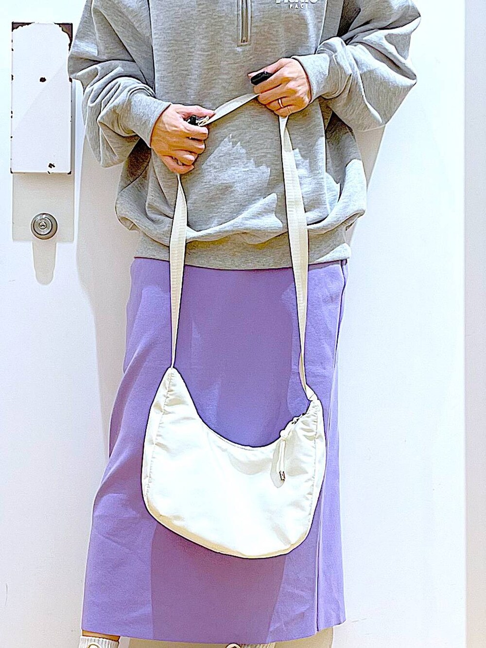 グレー系のスウェット、ベージュ系のスニーカー、ホワイト系のショルダーバッグを着用したレディースの春コーディネートの9枚目の写真