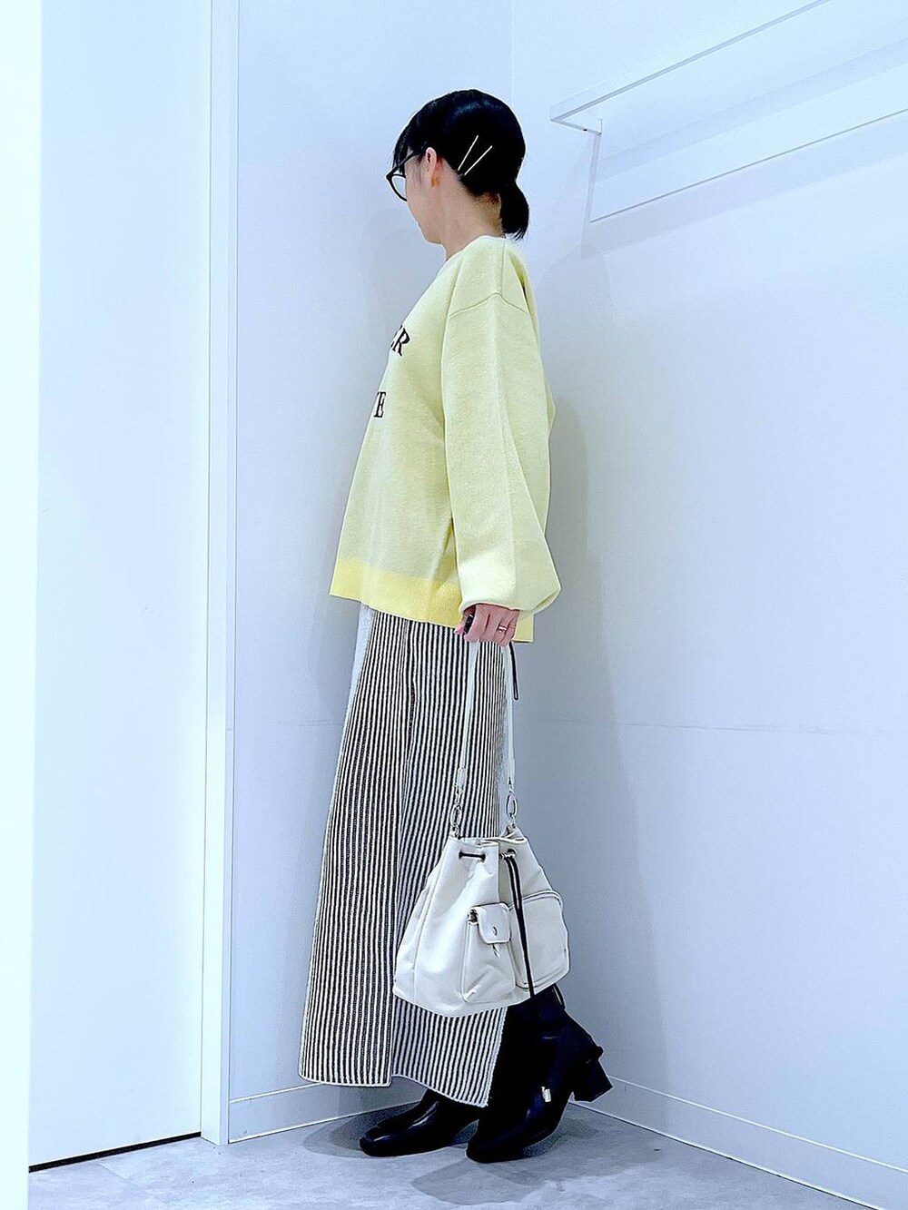 ホワイト系のショルダーバッグ、ベージュ系のスカート、ブラック系のブーツを着用したレディースの冬コーディネートの3枚目の写真