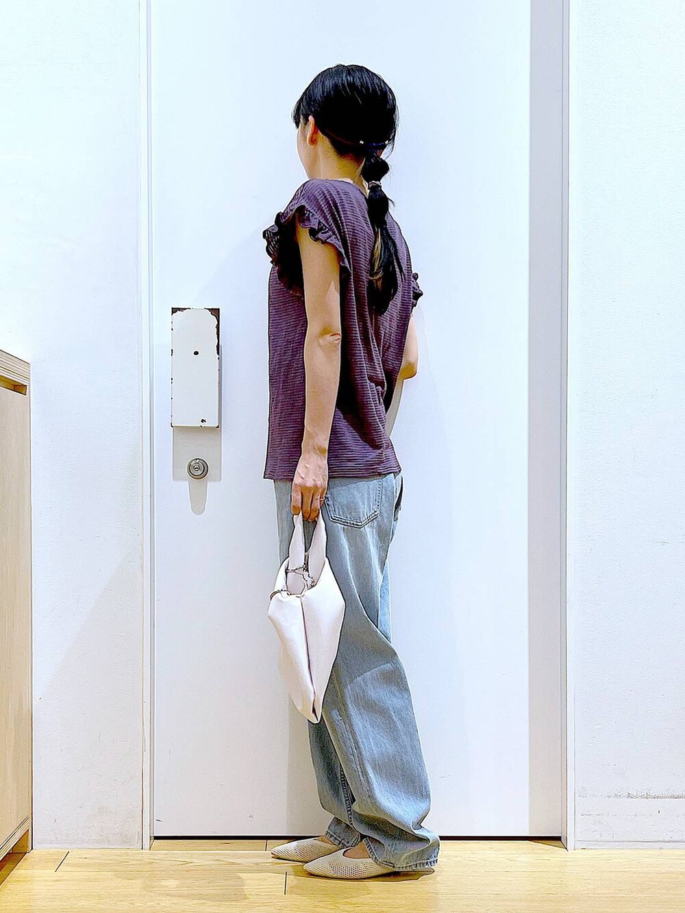 ホワイト系のショルダーバッグ、ブルー系のデニムパンツ、ホワイト系のパンプスを着用したレディースの春コーディネートの2枚目の写真