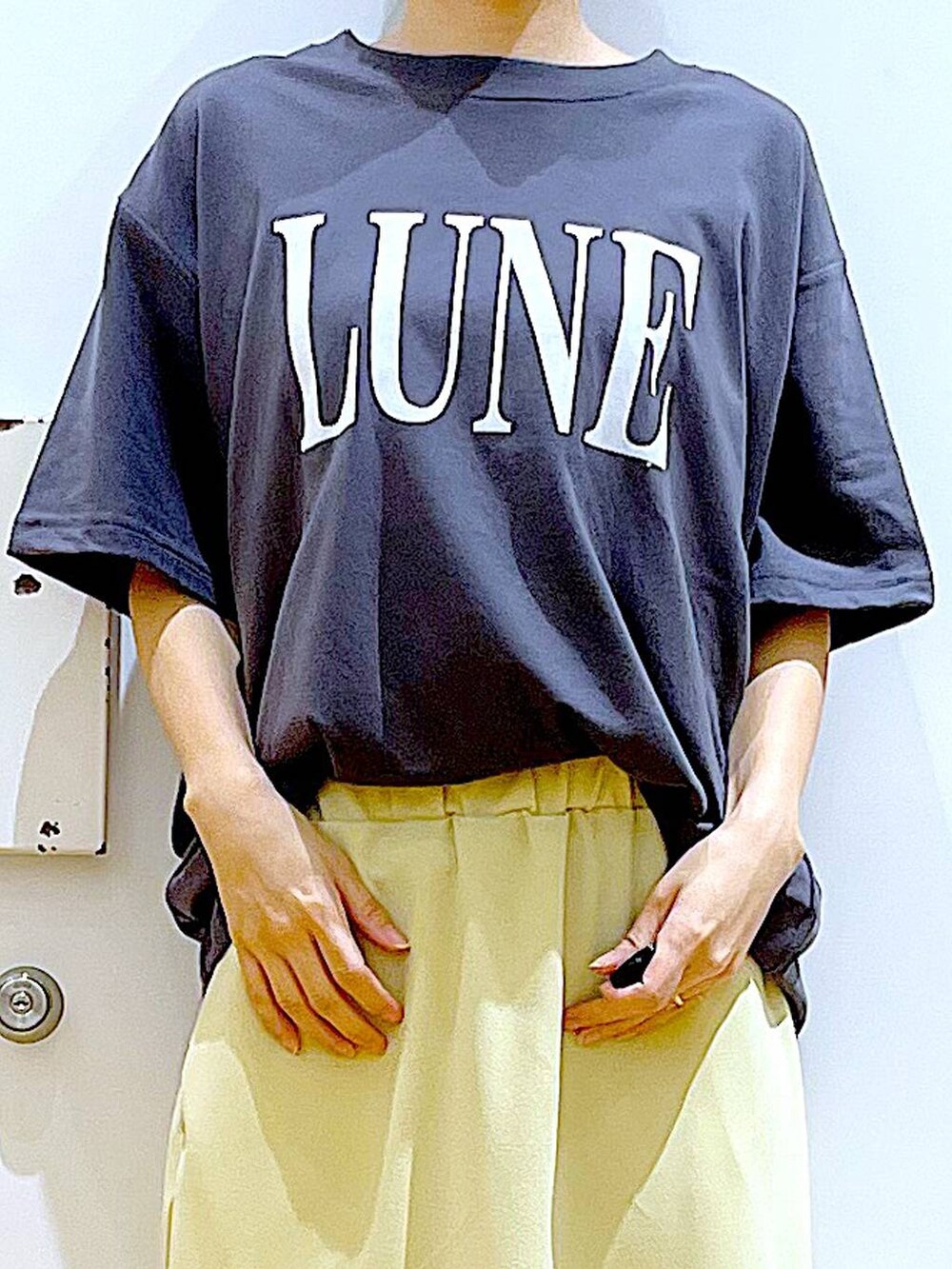 ホワイト系のショルダーバッグ、ベージュ系のパンプス、イエロー系のスカートを着用したレディースの夏コーディネートの7枚目の写真