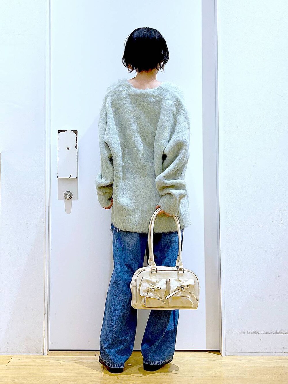 グリーン系のカーディガン/ボレロ、ブラック系のローファー、ブルー系のデニムパンツを着用したレディースの秋コーディネートの5枚目の写真