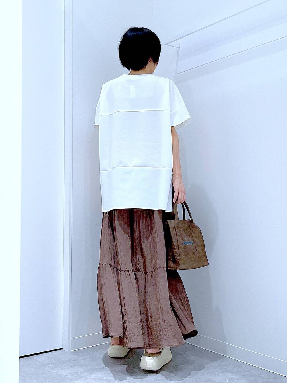 ホワイト系のサンダル、ホワイト系のTシャツ/カットソー、ブラウン系のスカートを着用したレディースの夏コーディネートの5枚目の写真