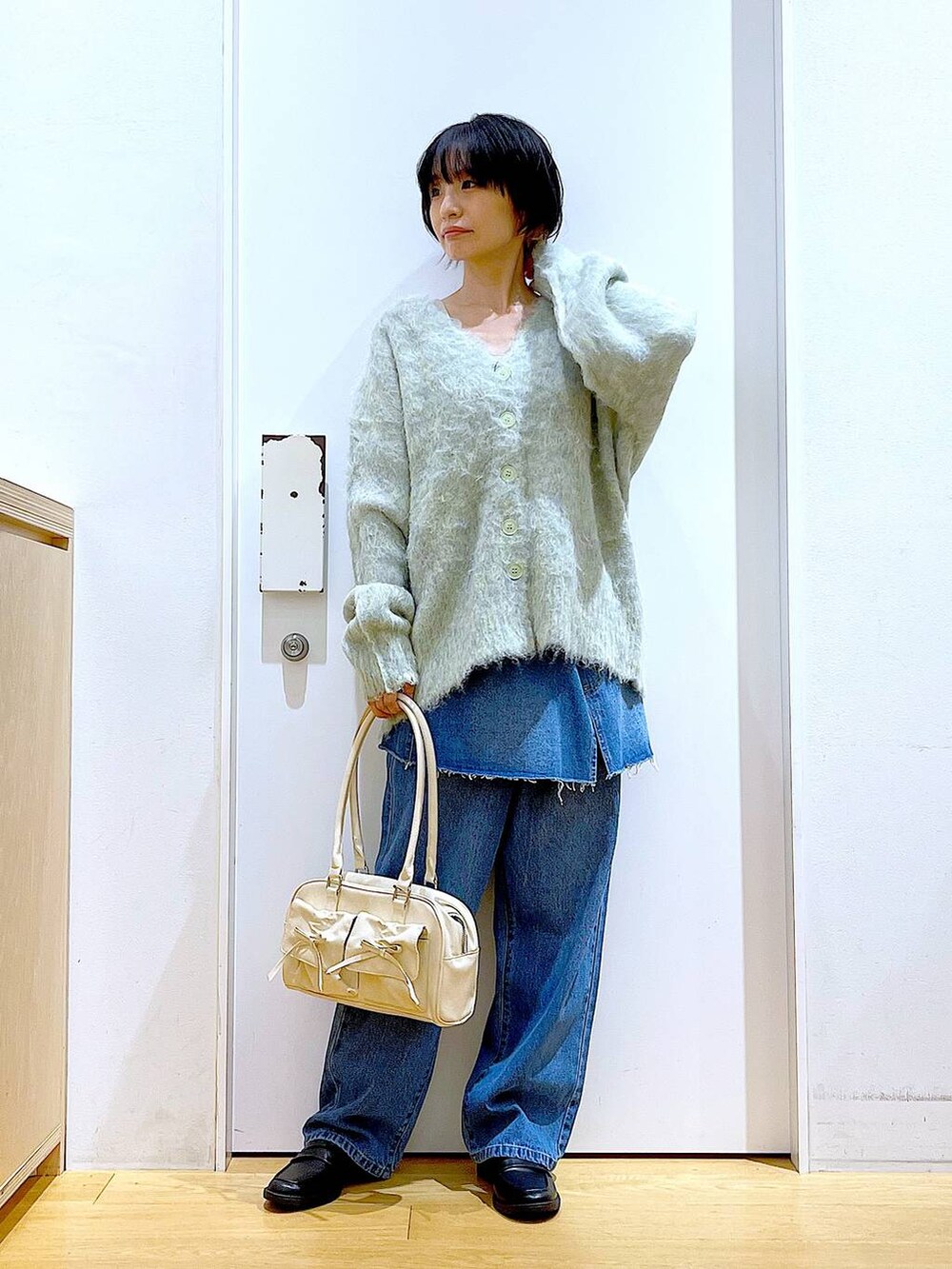 グリーン系のカーディガン/ボレロ、ブラック系のローファー、ブルー系のデニムパンツを着用したレディースの秋コーディネートの2枚目の写真