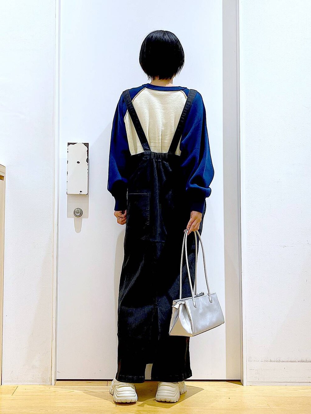 グレー系のジャンパースカート、シルバー系のトートバッグ、ベージュ系のブーツを着用したレディースの冬コーディネートの5枚目の写真