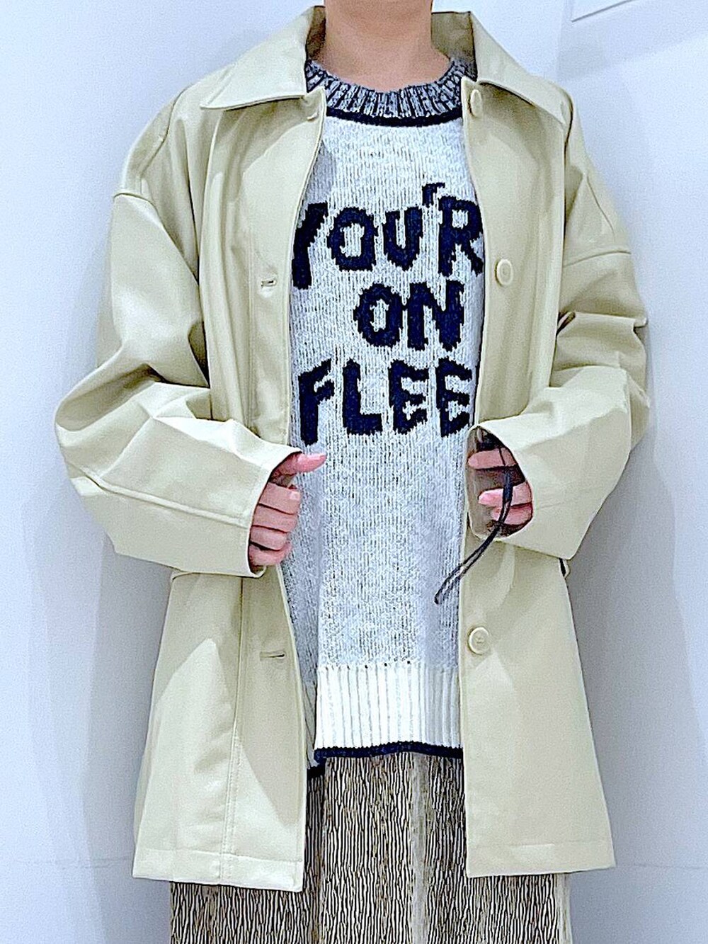 ベージュ系のステンカラーコート、ブラック系のブーツ、ホワイト系のショルダーバッグを着用したレディースの冬コーディネートの7枚目の写真