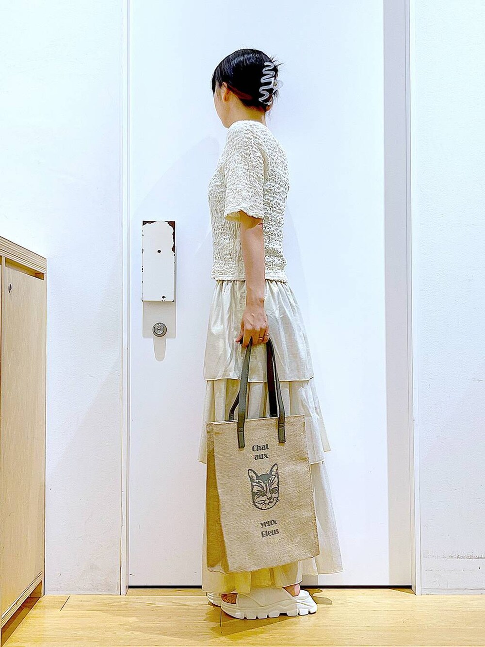 ホワイト系のサンダル、グレー系のトートバッグ、ゴールド系のスカートを着用したレディースの夏コーディネートの3枚目の写真