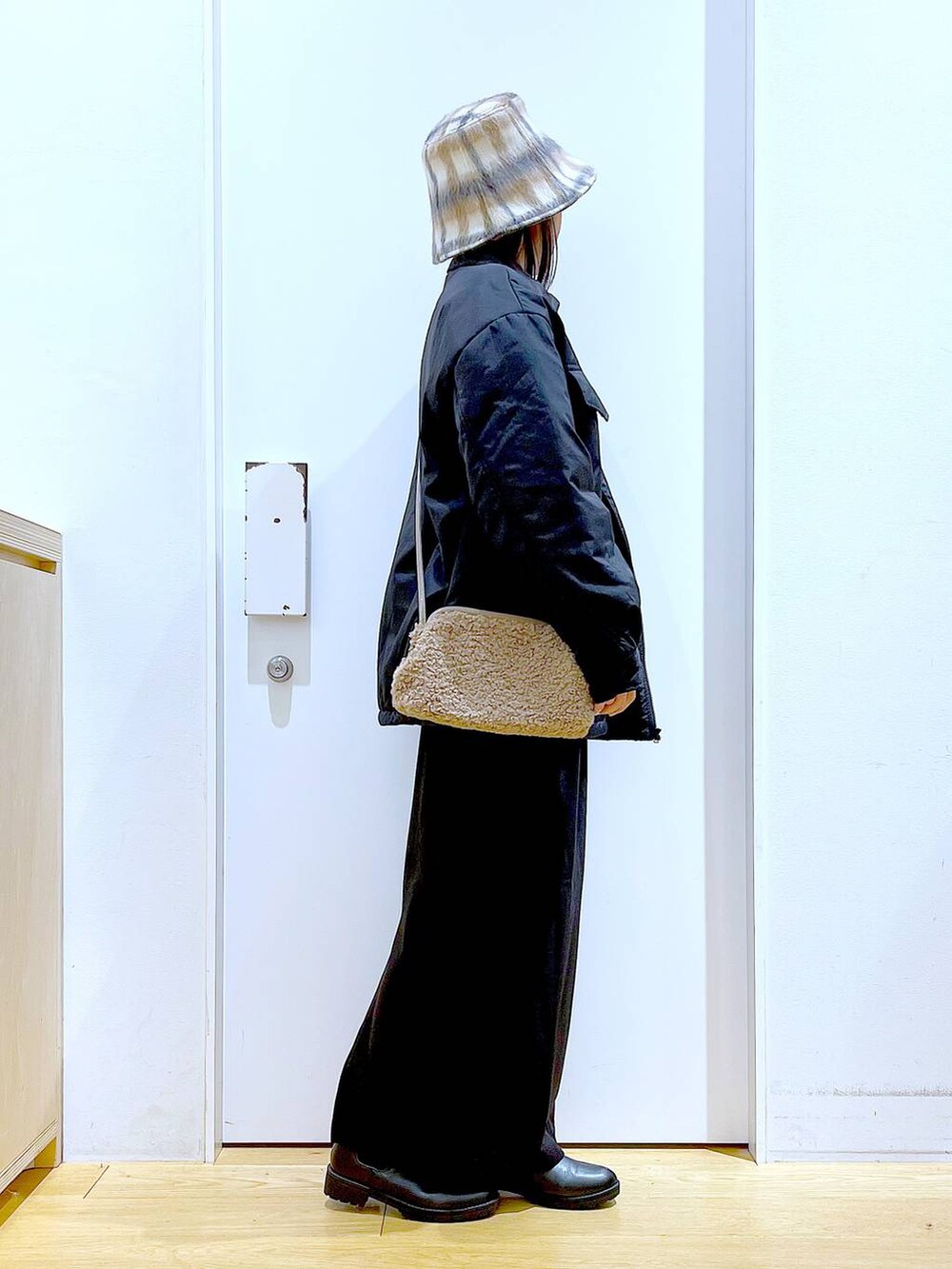 ブラック系のブルゾン、ブラック系のブーツ、ブラウン系のクラッチバッグを着用したレディースの冬コーディネートの4枚目の写真