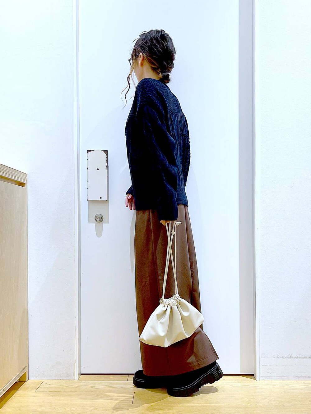 ブラック系のブーツ、ベージュ系のショルダーバッグ、ブラウン系のスカートを着用したレディースの冬コーディネートの3枚目の写真