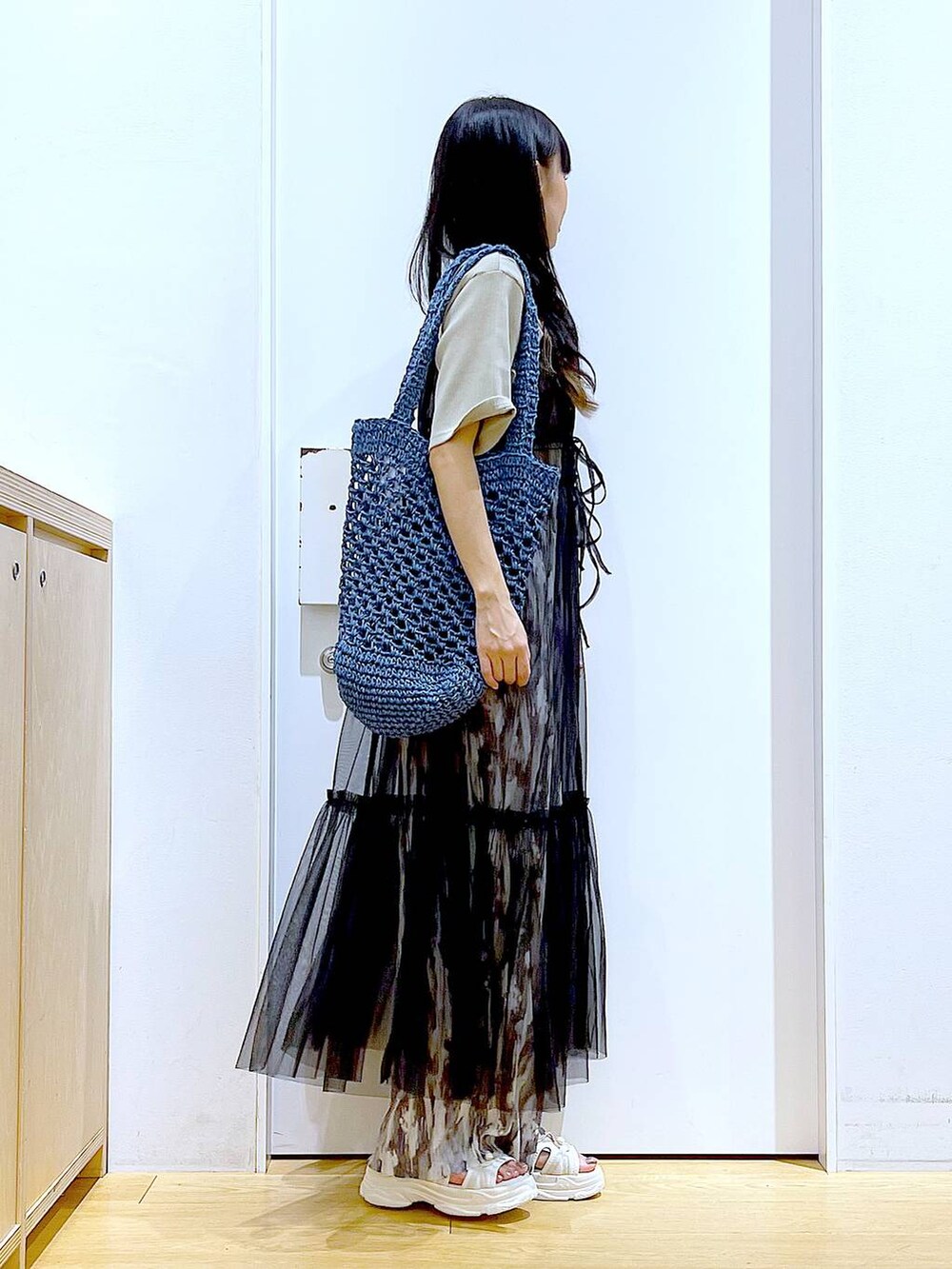 ブラック系のワンピース、ホワイト系のサンダル、ブルー系のトートバッグを着用したレディースの夏コーディネートの4枚目の写真