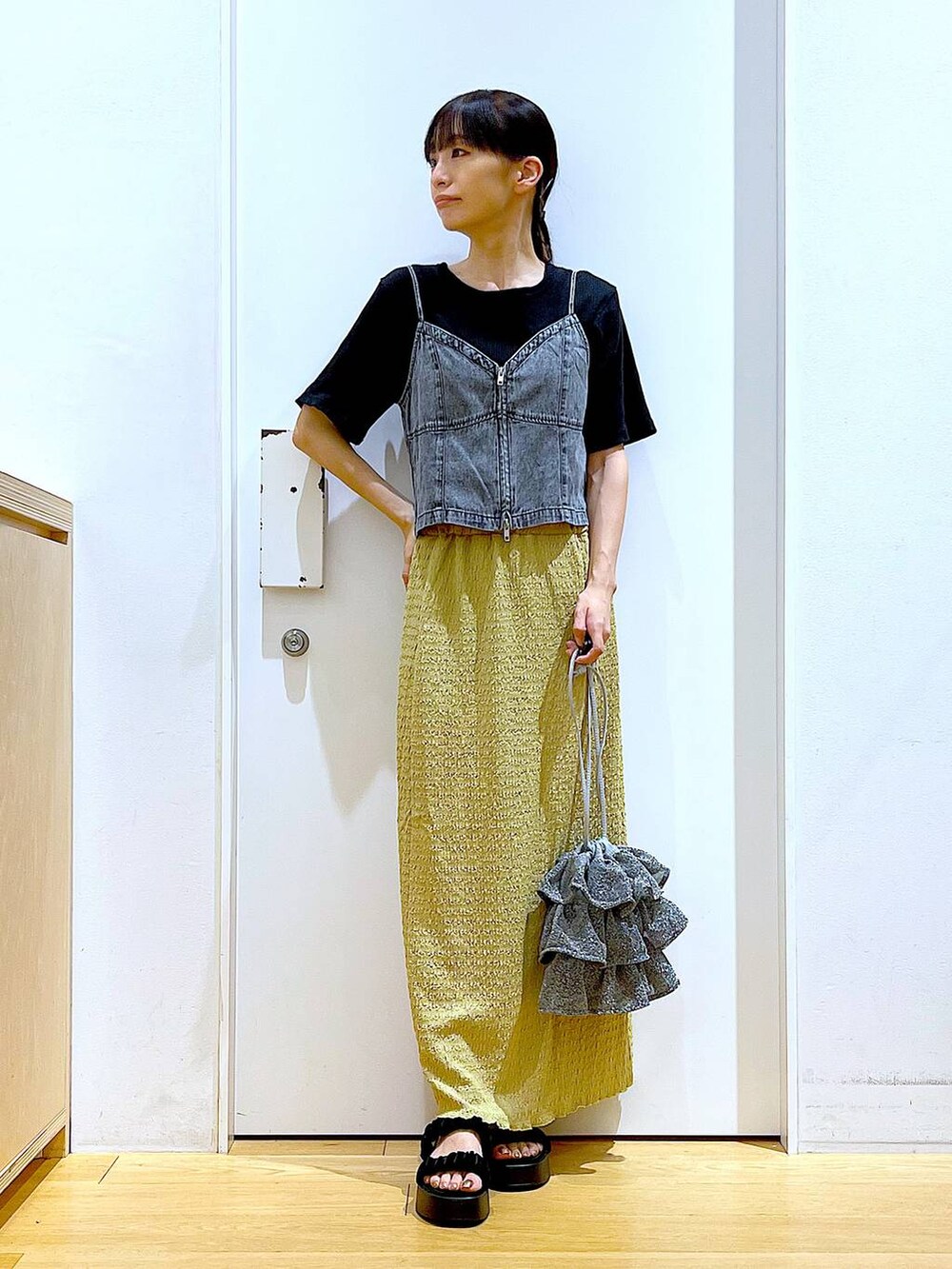 シルバー系のショルダーバッグ、グリーン系のスカート、ブラック系のTシャツ/カットソーを着用したレディースの夏コーディネートの2枚目の写真