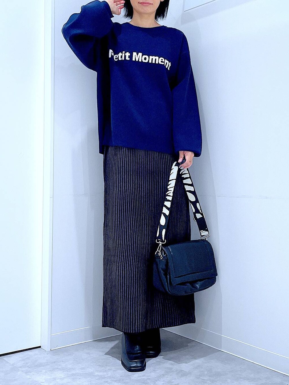 ブラック系のスカート、ブラック系のショルダーバッグ、ブラック系のブーツを着用したレディースの冬コーディネートの6枚目の写真