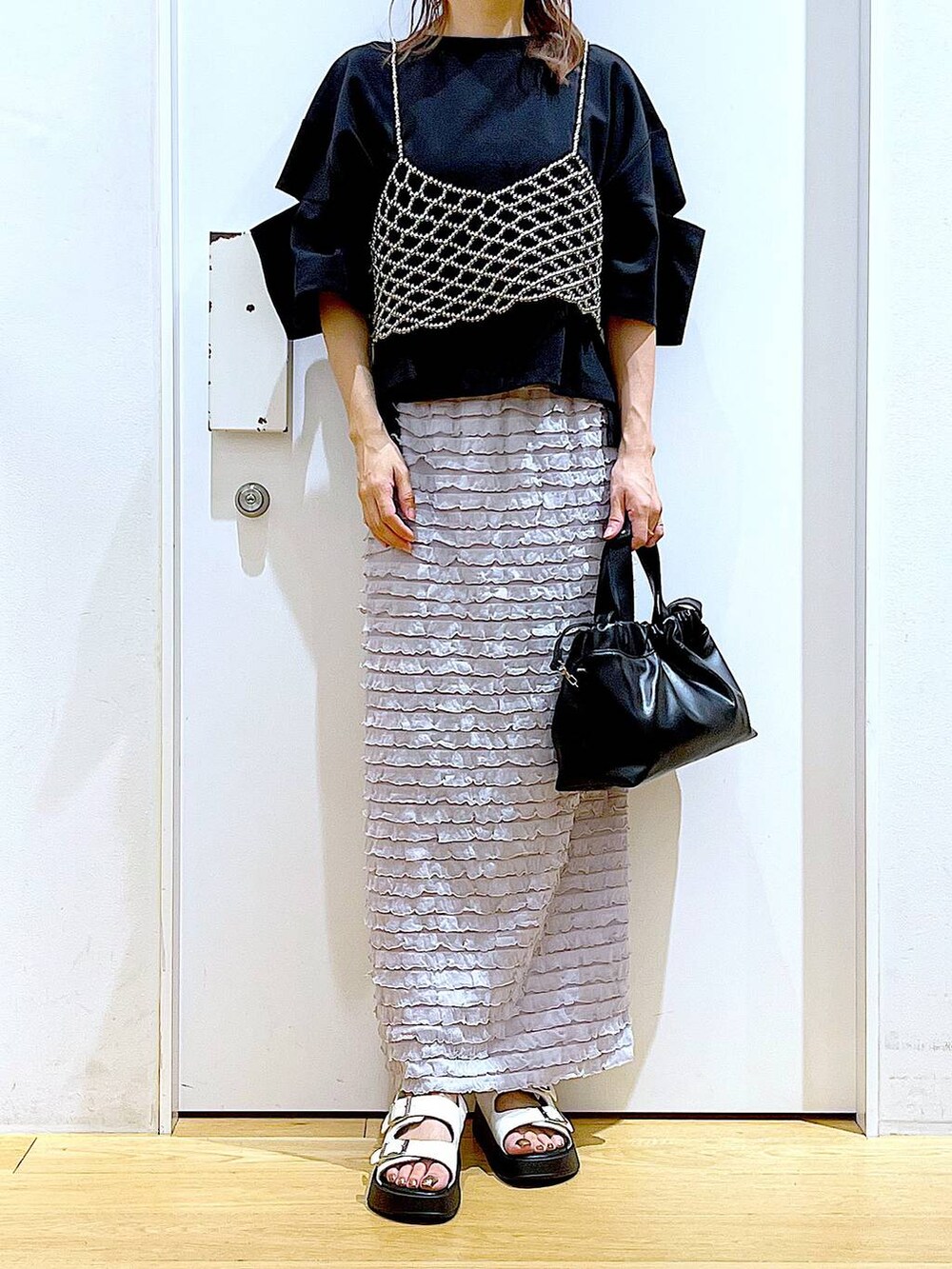 ホワイト系のサンダル、ブラック系のショルダーバッグ、シルバー系のベストを着用したレディースの夏コーディネートの6枚目の写真