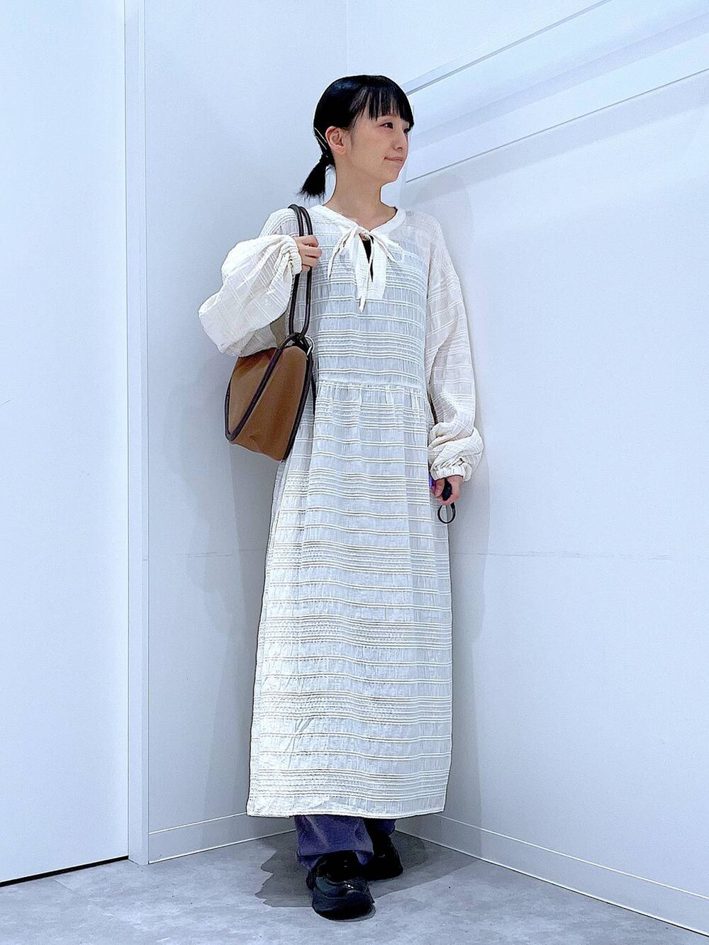 ブラック系のローファー、ブラウン系のショルダーバッグ、ベージュ系のワンピースを着用したレディースの秋コーディネートの2枚目の写真