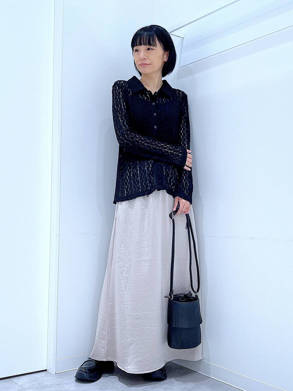 ブラック系のローファー、ブラック系のショルダーバッグ、ベージュ系のスカートを着用したレディースの秋コーディネートの2枚目の写真