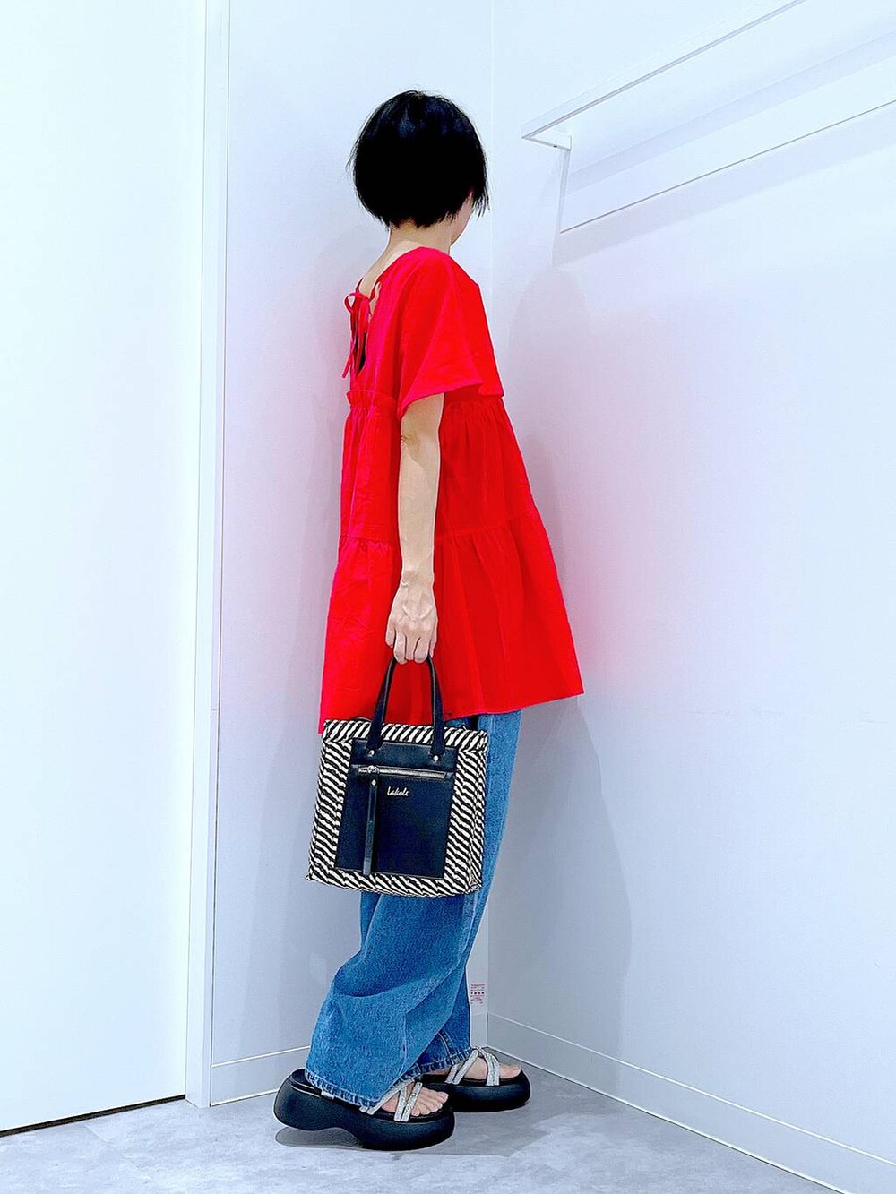 ブルー系のデニムパンツ、ブラック系のショルダーバッグ、シルバー系のサンダルを着用したレディースの夏コーディネートの4枚目の写真