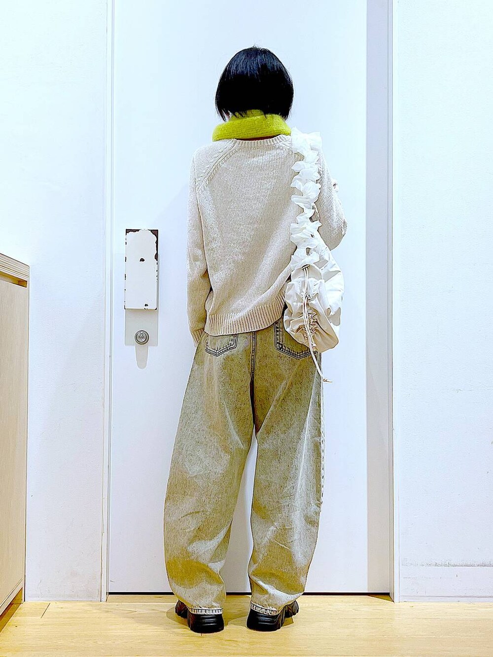 ホワイト系のショルダーバッグ、ブラック系のブーツ、ベージュ系のデニムパンツを着用したレディースの冬コーディネートの5枚目の写真