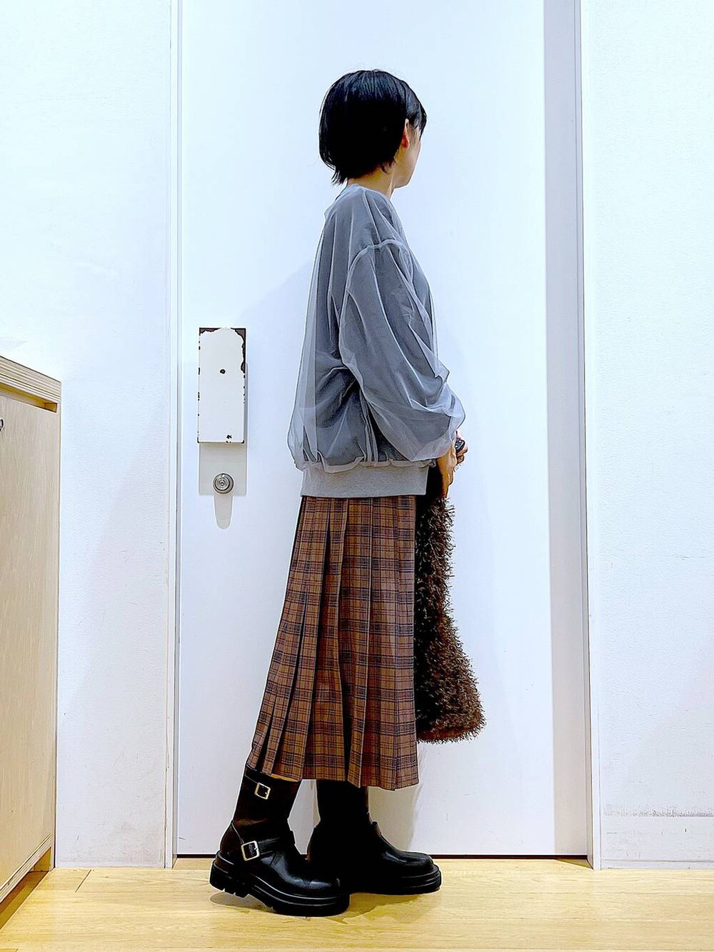 ブラック系のブーツ、ブラウン系のショルダーバッグ、ブラウン系のスカートを着用したレディースの秋コーディネートの4枚目の写真