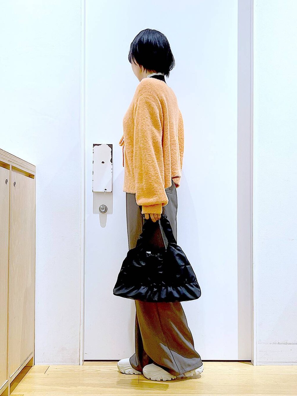 ブラック系のニット/セーター、ベージュ系のブーツ、ブラック系のショルダーバッグを着用したレディースの冬コーディネートの3枚目の写真