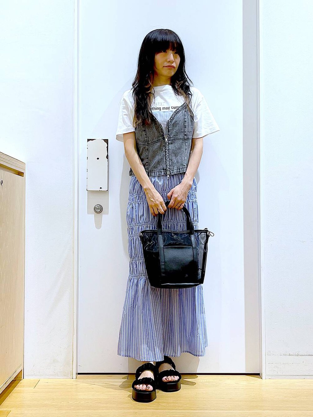 ブラック系のサンダル、ブラック系のトートバッグ、グレー系のベストを着用したレディースの夏コーディネートの2枚目の写真