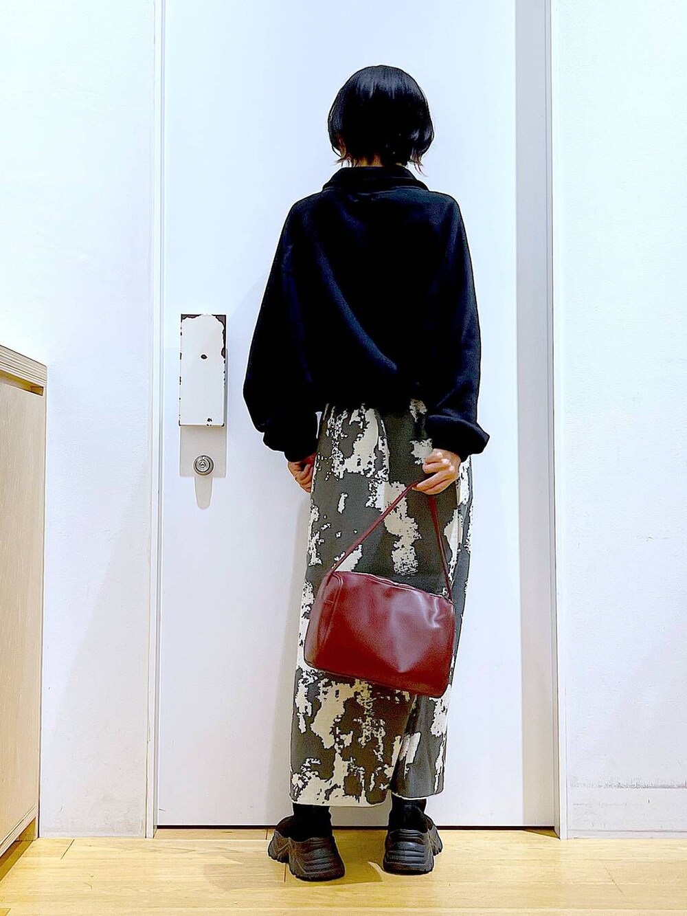 グレー系のスカート、レッド系のショルダーバッグ、ブラック系のブーツを着用したレディースの冬コーディネートの5枚目の写真