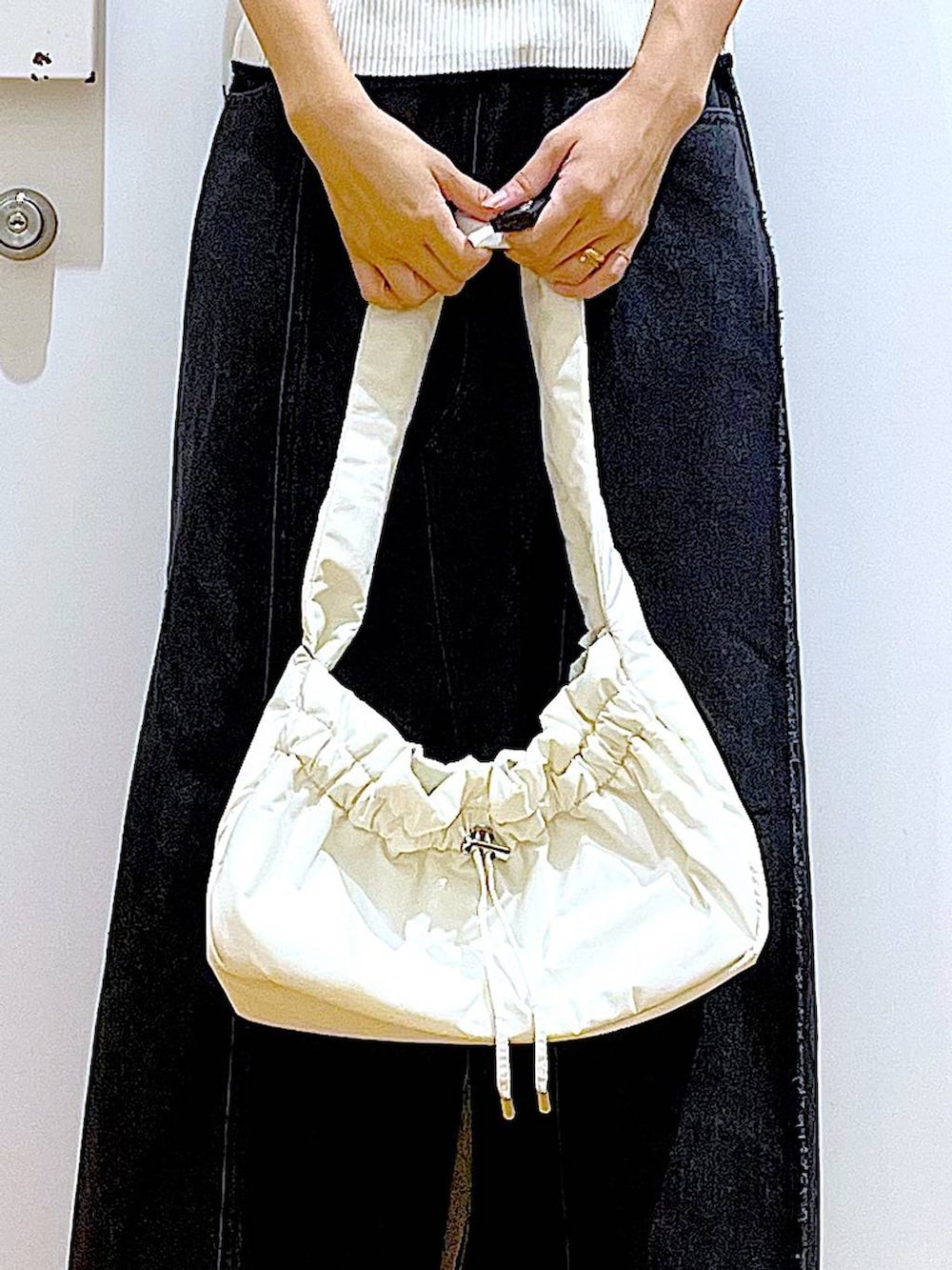 ホワイト系のハンドバッグ、ブラック系のローファー、ホワイト系のニット/セーターを着用したレディースの秋コーディネートの9枚目の写真