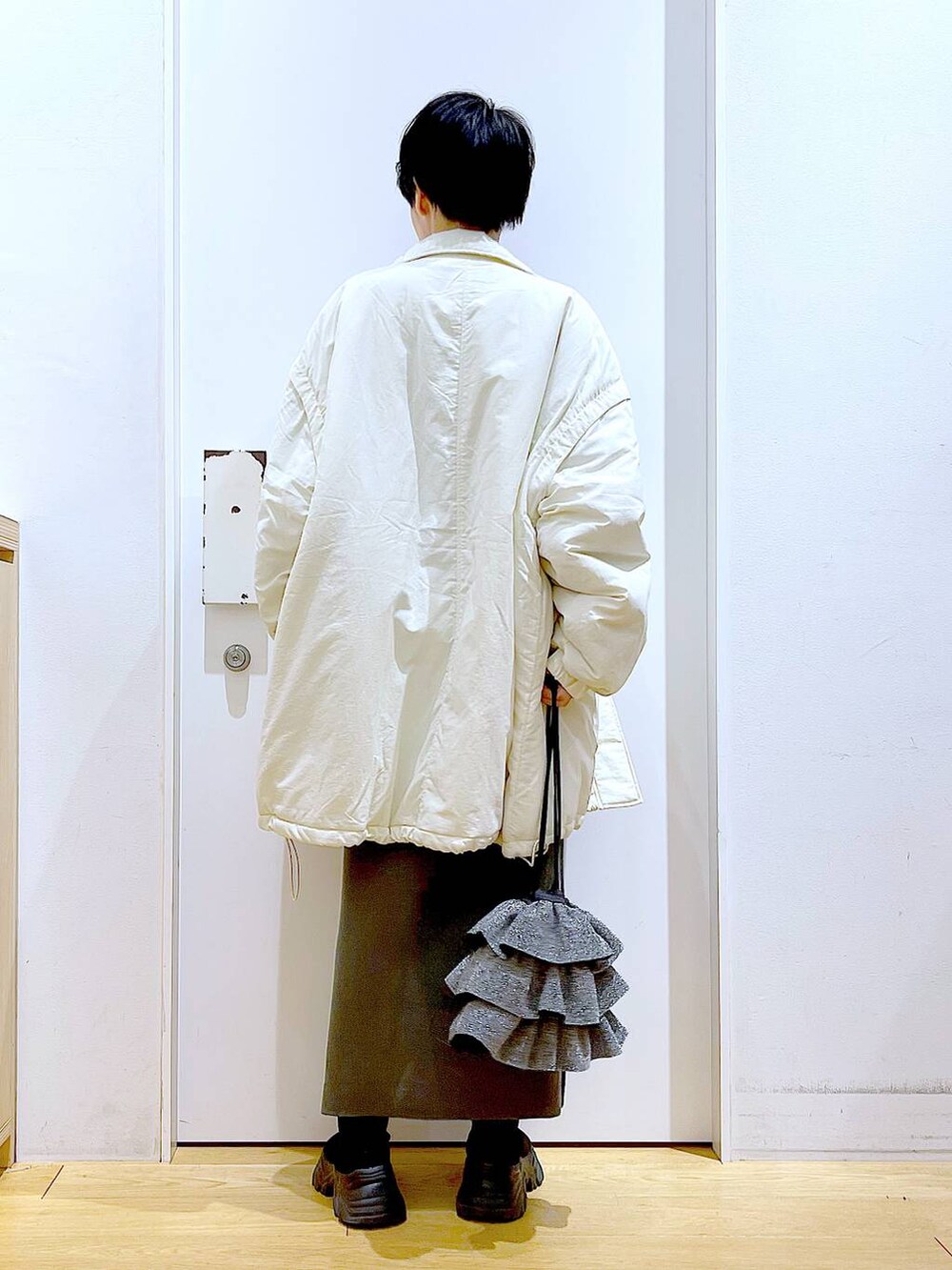 グレー系のスカート、ブラック系のブーツ、ホワイト系のその他アウターを着用したレディースの冬コーディネートの5枚目の写真