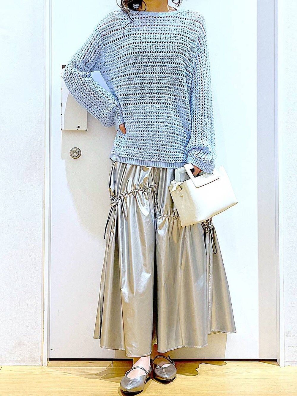 ブルー系のニット/セーター、シルバー系のスカート、ホワイト系のショルダーバッグを着用したレディースの春コーディネートの6枚目の写真