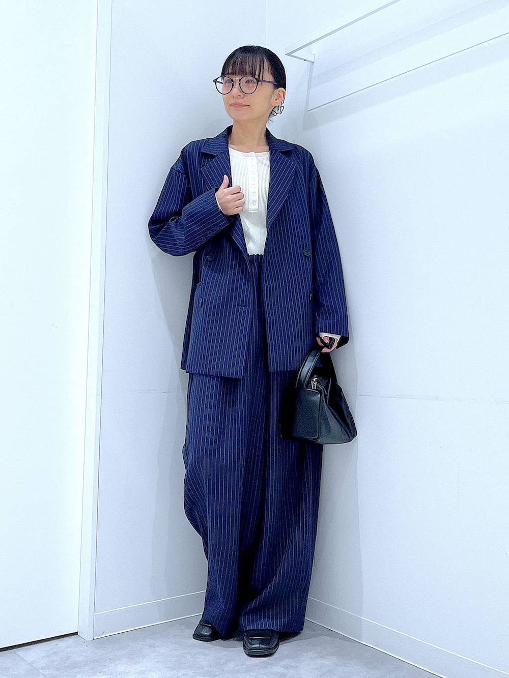 ブラック系のブーツ、ブラック系のショルダーバッグ、ブルー系のスラックスを着用したレディースの冬コーディネートの2枚目の写真